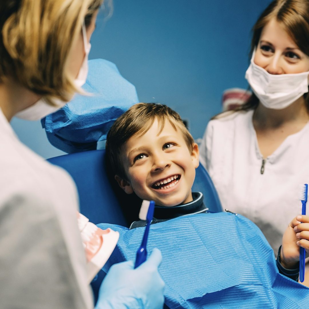 Dentistas enseñando a un niño como debe lavarse los dientes.